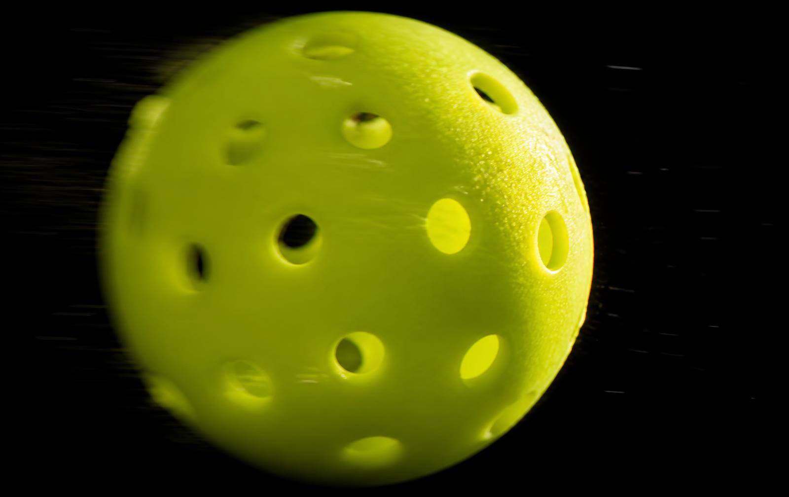Close-up of a neon pickleball in flight